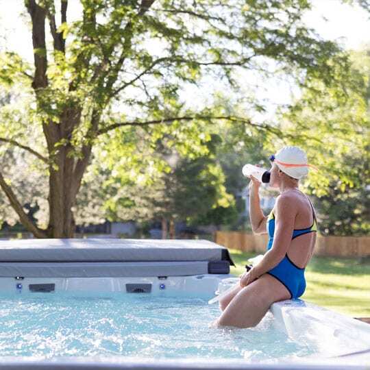 Donna che si idrata sul lato della sua swim spa.