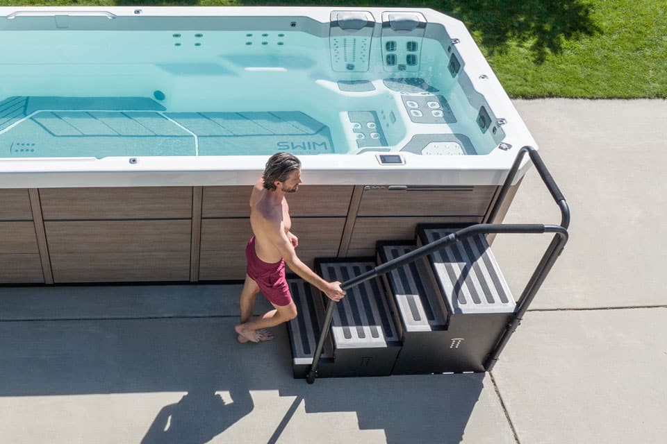 Man walking up steps to get into swim spa.